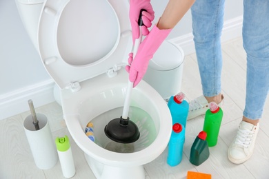 Photo of Woman cleaning toilet bowl in bathroom