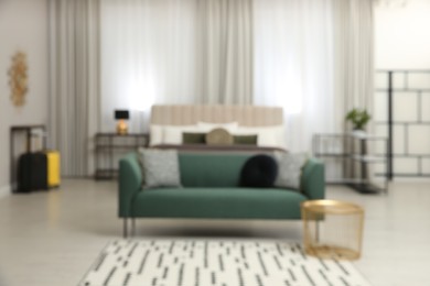 Photo of Blurred view of beautiful hotel room interior with green sofa