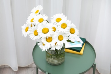 Vase with beautiful chamomile flowers on table