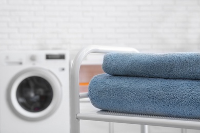 Photo of Folded clean terry towels on table in laundry room, closeup. Space for text