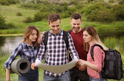 Group of young people exploring map in wilderness. Camping season