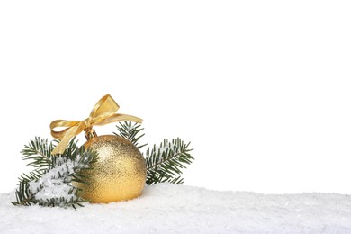 Beautiful golden Christmas ball with bow and fir tree branches on snow against white background