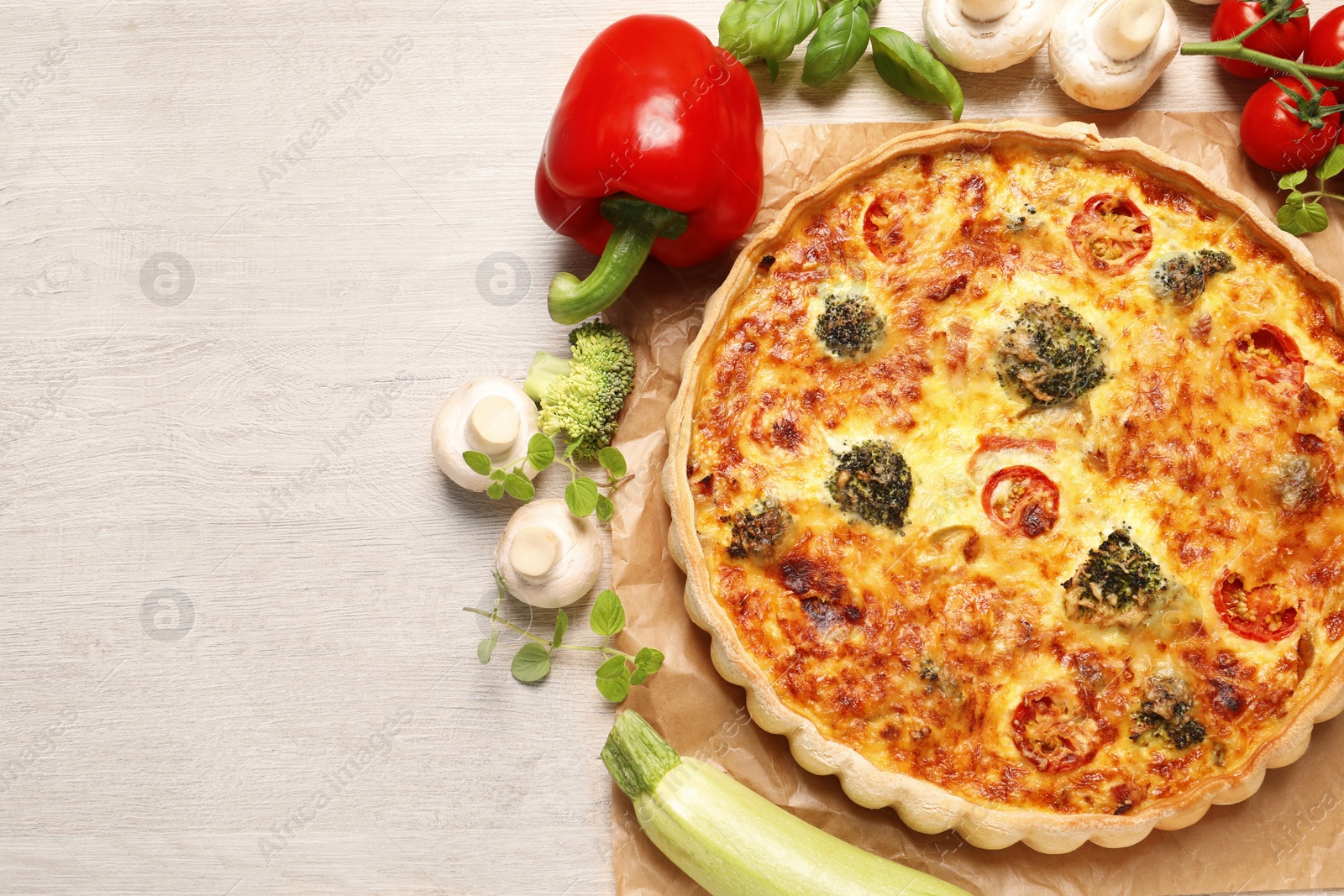 Photo of Delicious homemade vegetable quiche and ingredients on wooden table, flat lay. Space for text