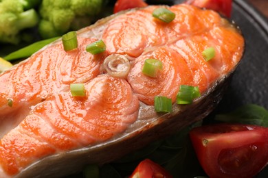 Healthy meal. Grilled salmon steak, green onion and vegetables on board, closeup