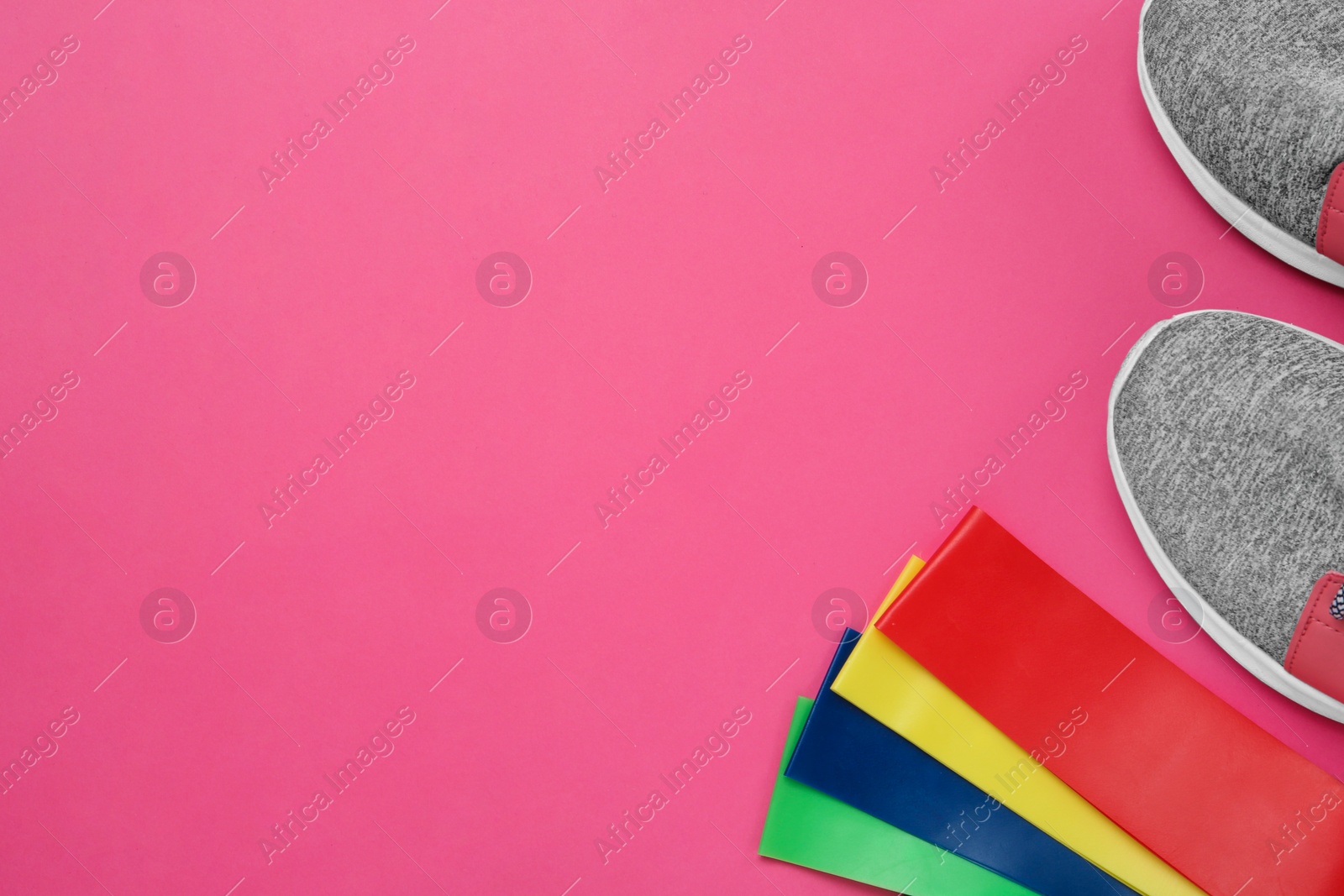 Photo of Set of fitness elastic bands and sneakers on pink background, flat lay. Space for text