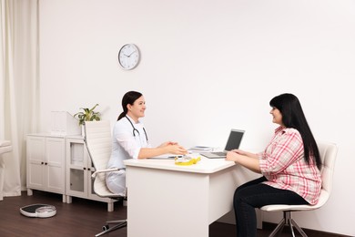 Photo of Overweight mature woman consulting with nutritionist in clinic