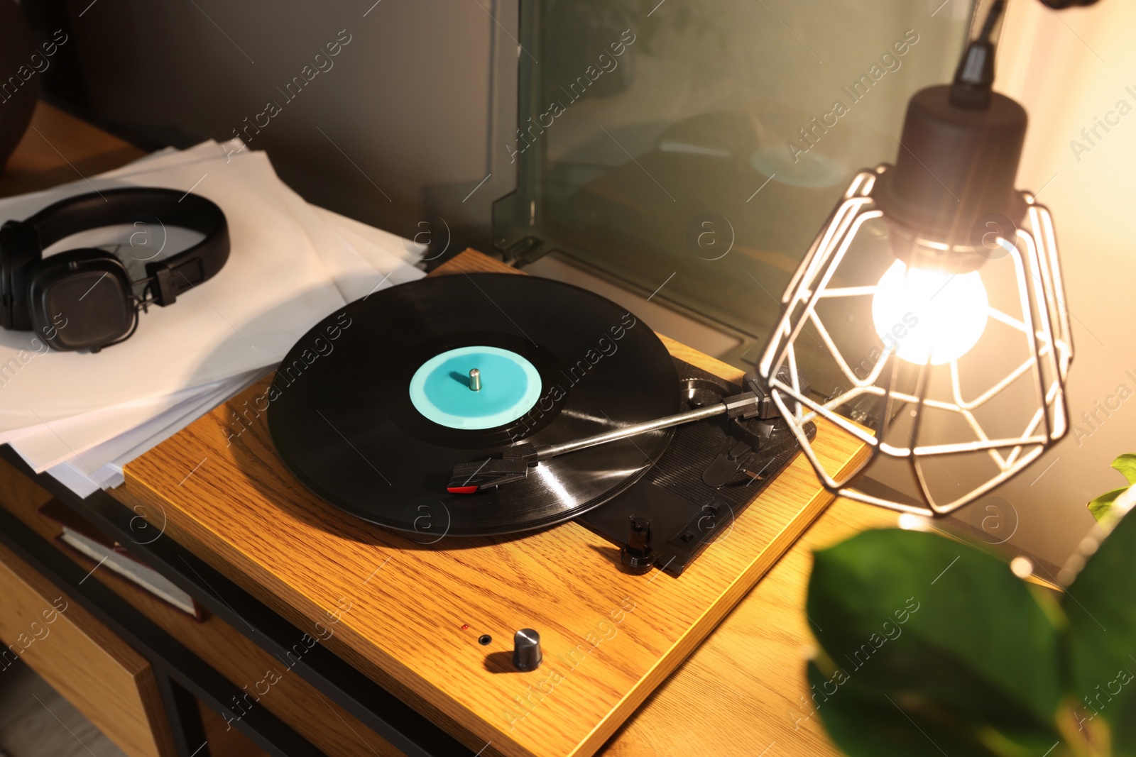 Photo of Stylish turntable with vinyl record on table indoors