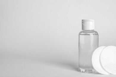 Photo of Bottle of micellar water and cotton pads on white background. Space for text