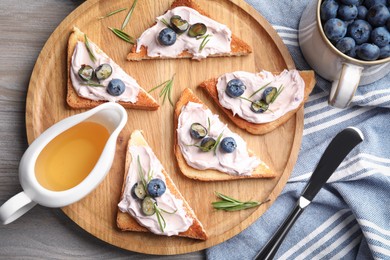 Tasty sandwiches with cream cheese, honey and berries on white wooden table, flat lay