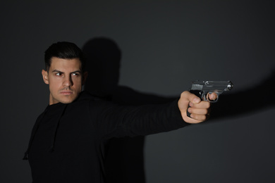 Professional killer with gun on black background