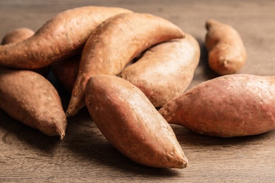 Photo of Pile of sweet potatoes on wooden background