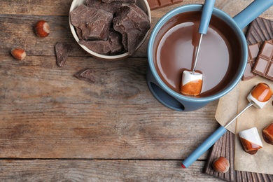 Photo of Flat lay composition with chocolate fondue and space for text on wooden background