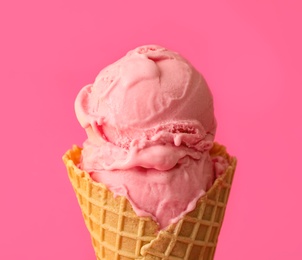 Photo of Delicious ice cream in waffle cone on pink background, closeup