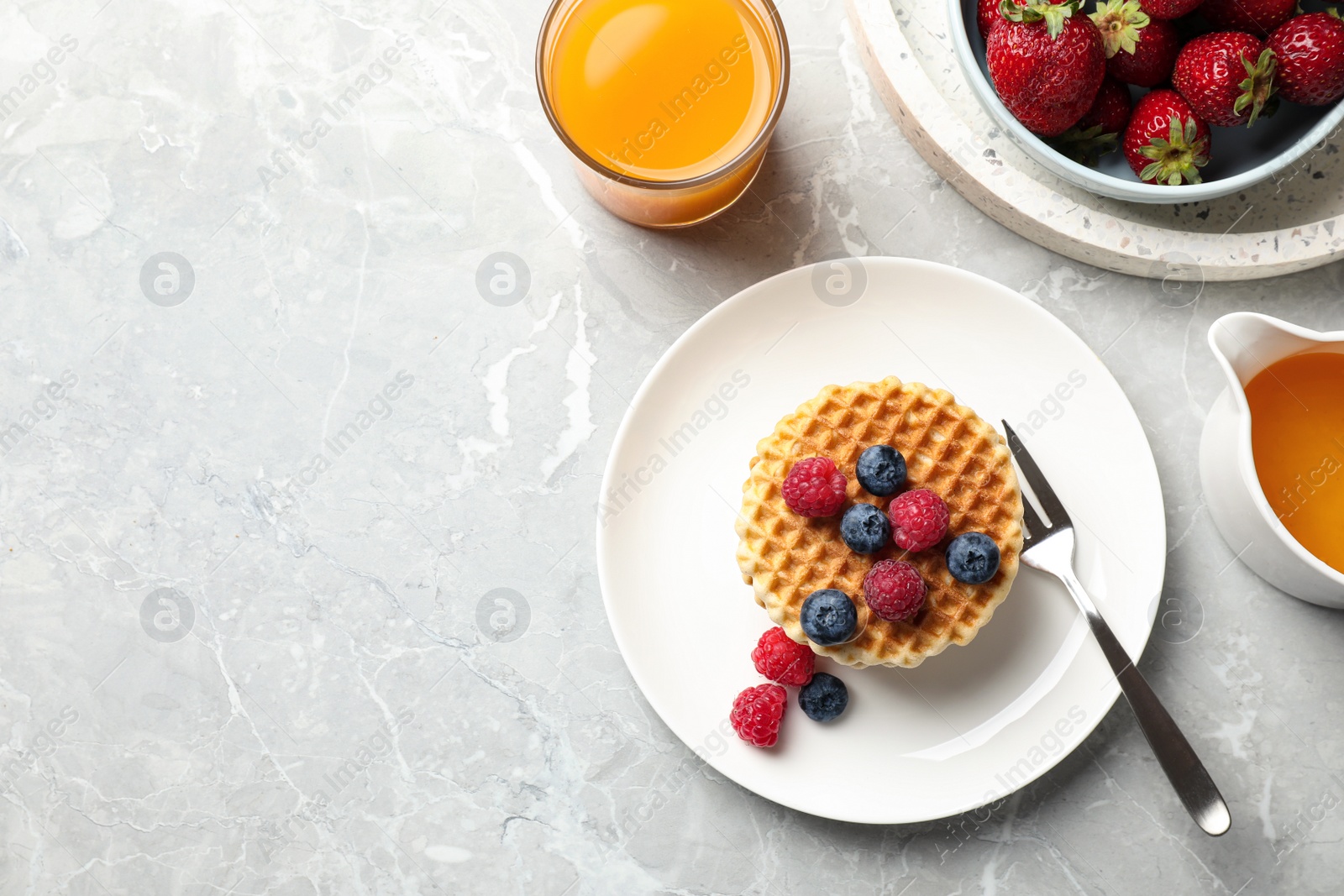 Photo of Tasty breakfast with wafers served on light grey marble table, flat lay. Space for text