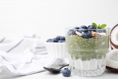 Photo of Tasty chia matcha pudding with coconut and blueberries on white table, space for text. Healthy breakfast