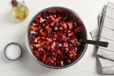 Photo of Bowl of delicious fresh vinaigrette salad, oil and salt on white wooden table, flat lay