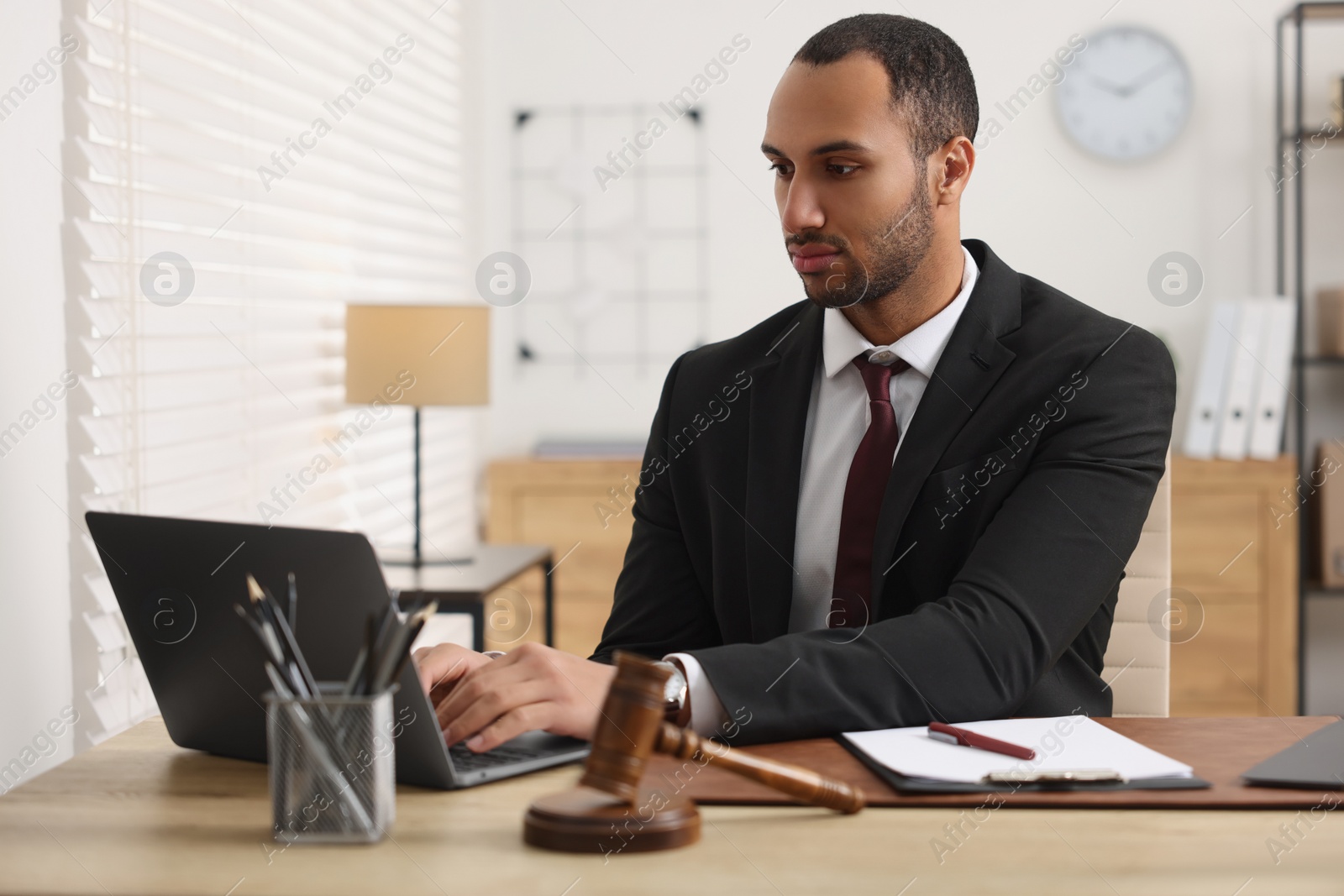 Photo of Serious lawyer working with laptop at table in office