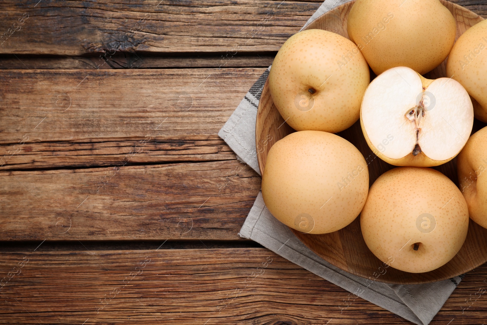 Photo of Cut and whole apple pears on wooden table, top view. Space for text