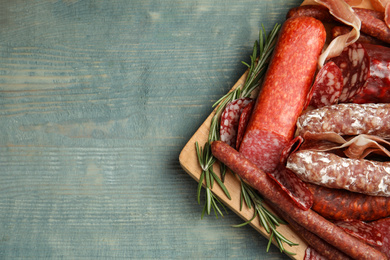 Photo of Different types of sausages served on light blue wooden table, top view. Space for text