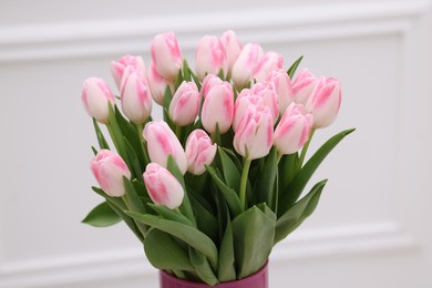 Photo of Beautiful bouquet of fresh pink tulips near white wall