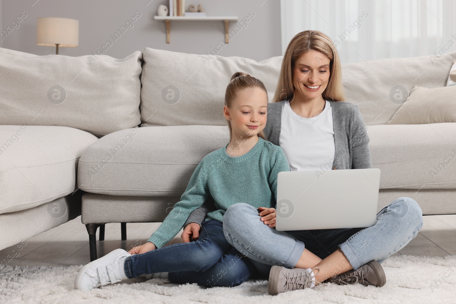 Photo of Happy woman and her daughter with laptop on floor at home