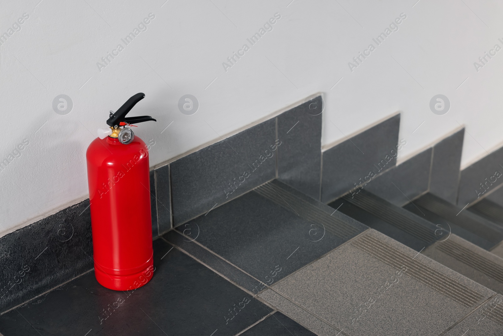 Photo of Red fire extinguisher near white wall, space for text