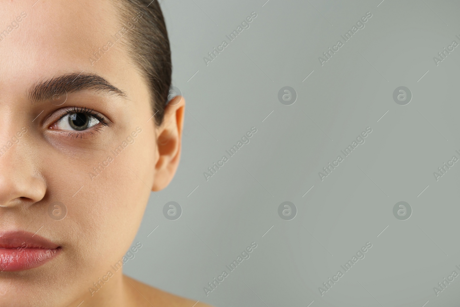 Photo of Young woman with perfect eyebrows on grey background, closeup. Space for text