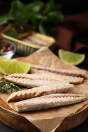 Photo of Canned mackerel fillets served on black table, closeup
