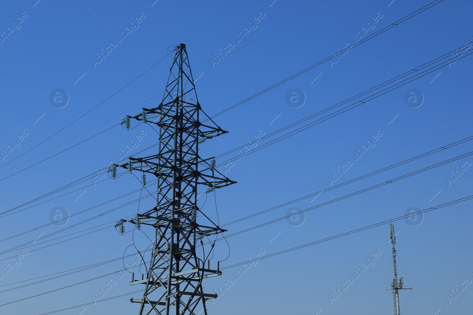 Photo of High voltage tower against blue sky on sunny day