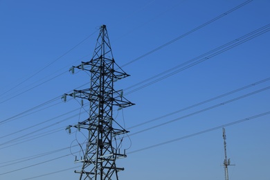 High voltage tower against blue sky on sunny day