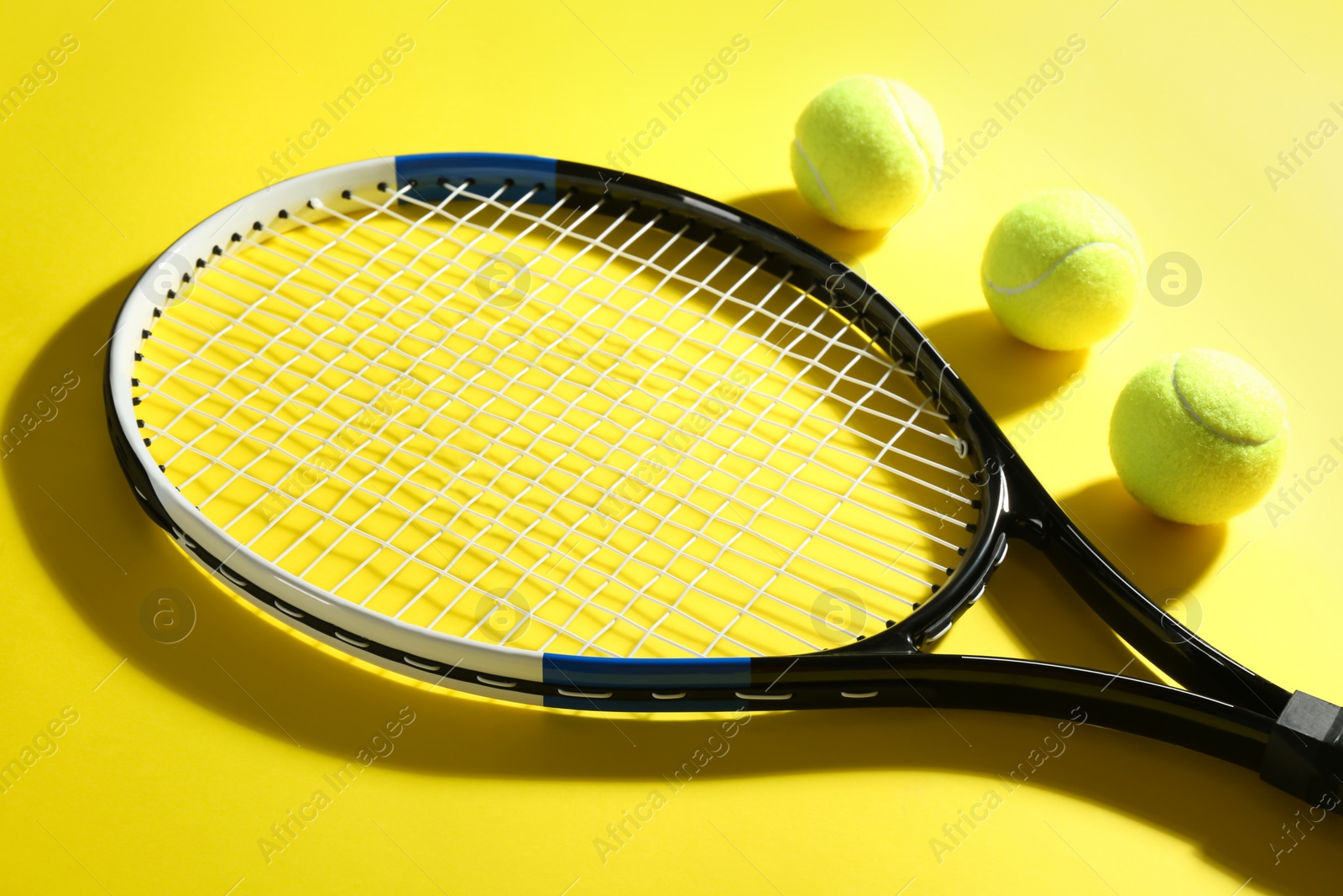 Photo of Tennis racket and balls on yellow background. Sports equipment