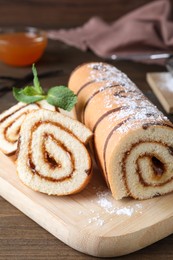 Tasty cake roll with jam on wooden table