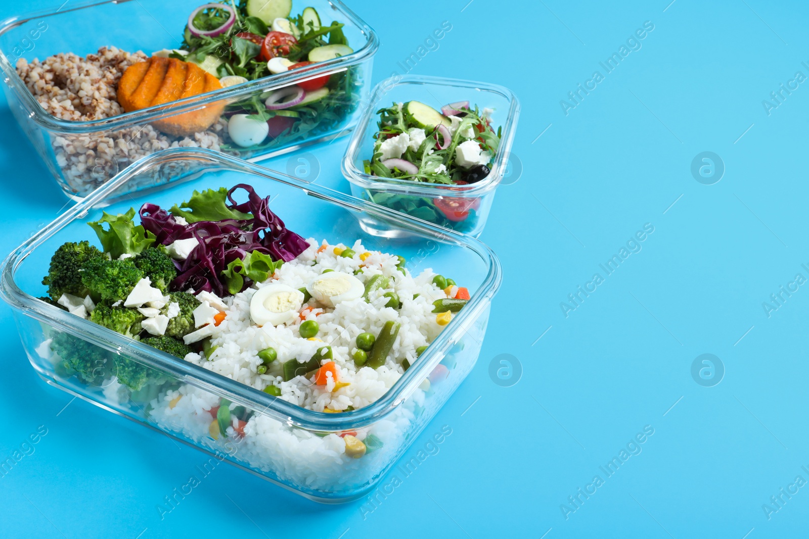 Photo of Set of glass containers with fresh food on light blue background, space for text