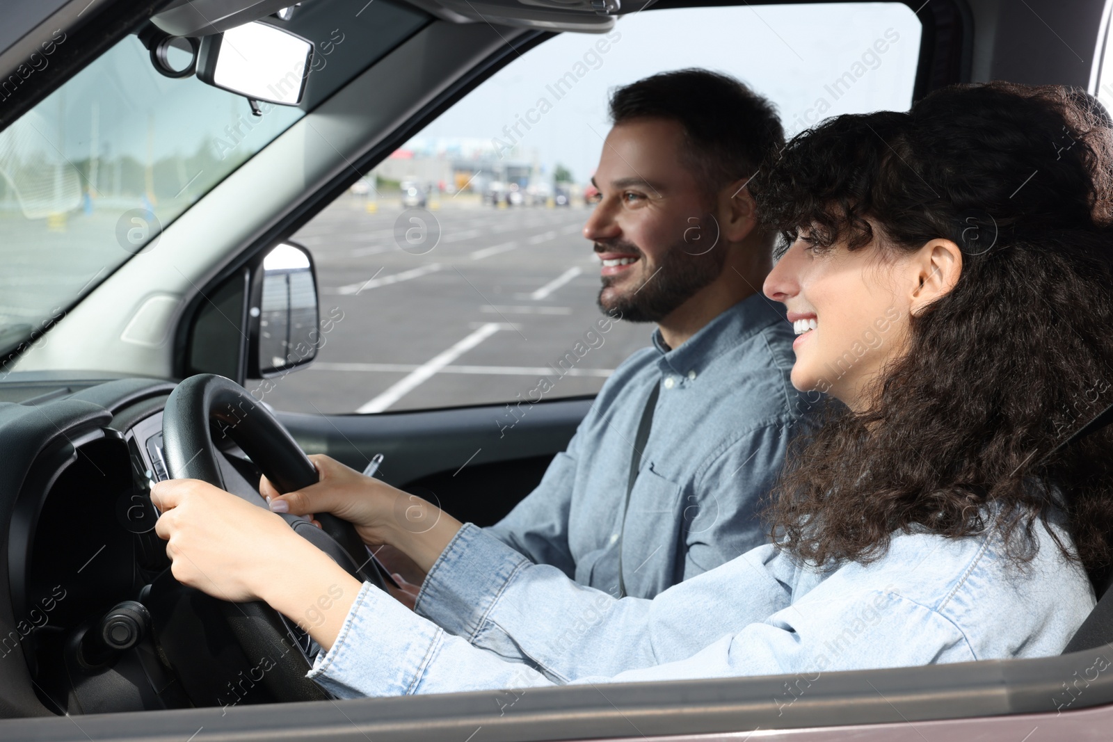 Photo of Driving school. Happy student passing driving test with examiner in car at parking lot