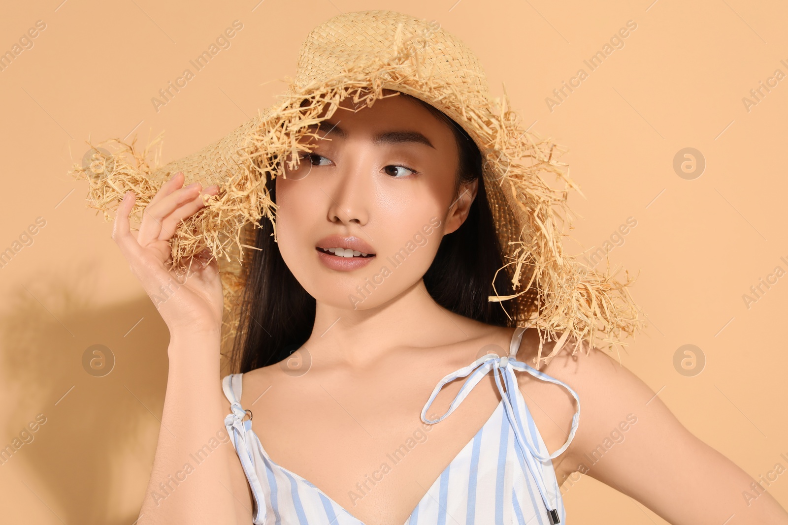 Photo of Beautiful young woman in straw hat on beige background