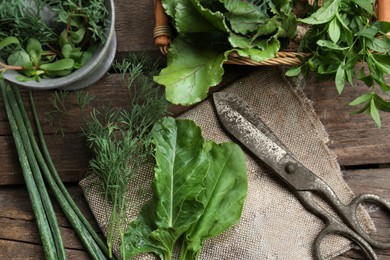 Flat lay composition with different herbs, rusty scissors and burlap fabric on wooden table