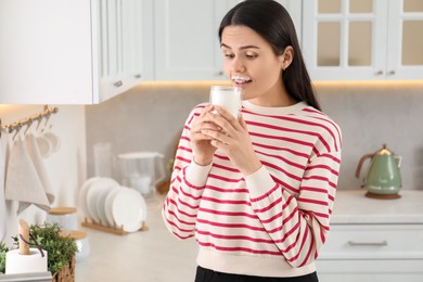 Photo of Cute woman with milk mustache drinking tasty dairy drink in kitchen. Space for text