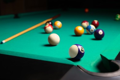 Many colorful billiard balls and cue on green table, space for text