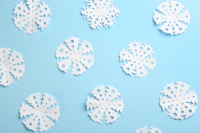 Many paper snowflakes on light blue background, flat lay