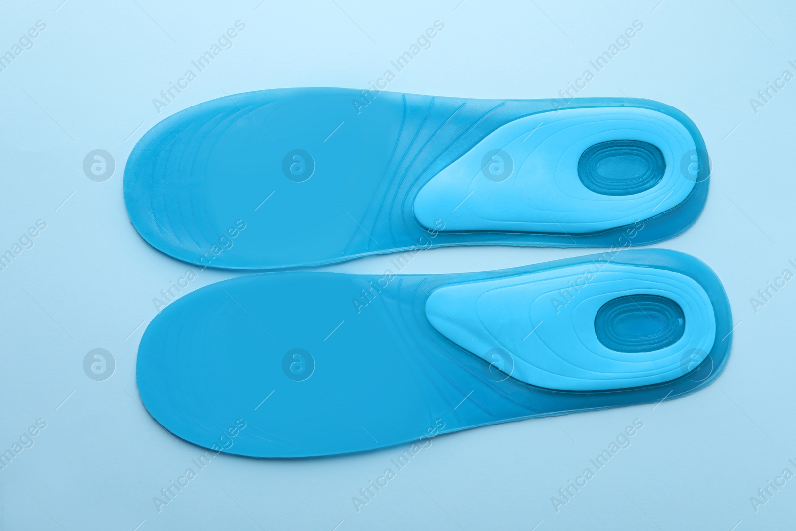 Photo of Turquoise orthopedic insoles on light blue background, flat lay