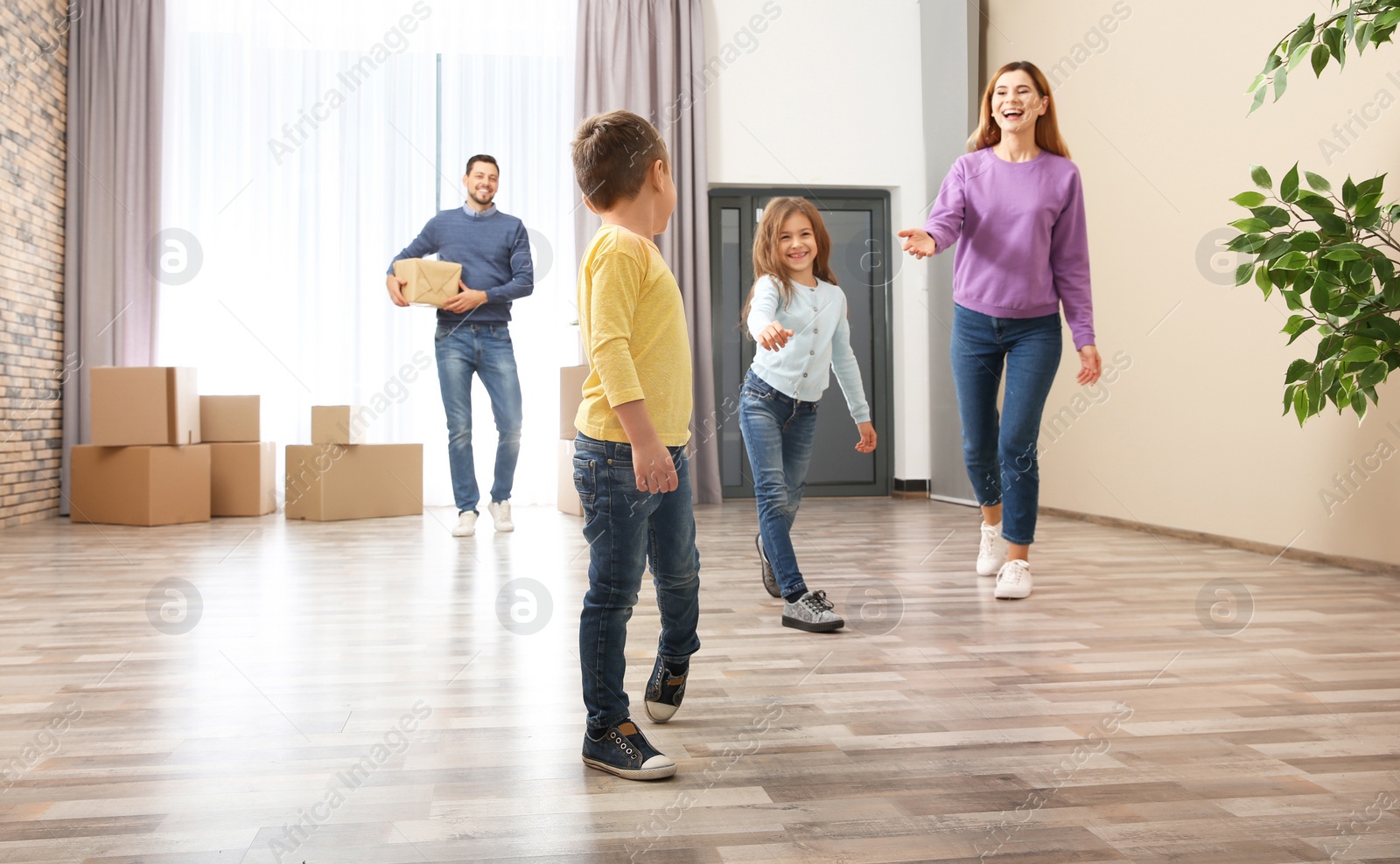 Photo of Happy family and pile of moving boxes in their new house