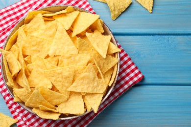 Photo of Tortilla chips (nachos) on light blue wooden table, flat lay