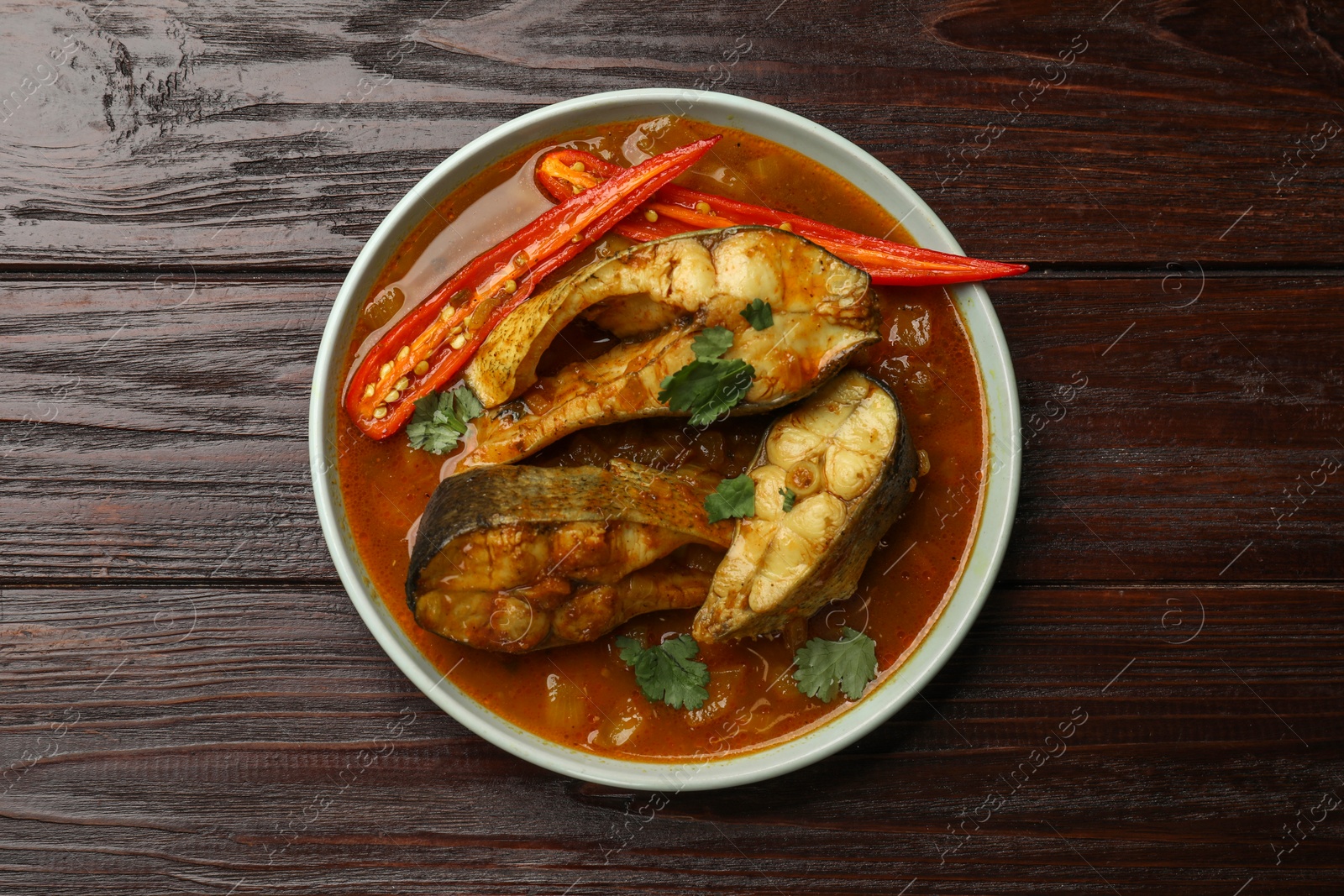 Photo of Tasty fish curry on wooden table, top view. Indian cuisine