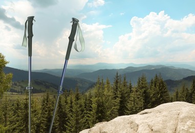 Image of Trekking poles and beautiful view of mountains on sunny day. Space for text