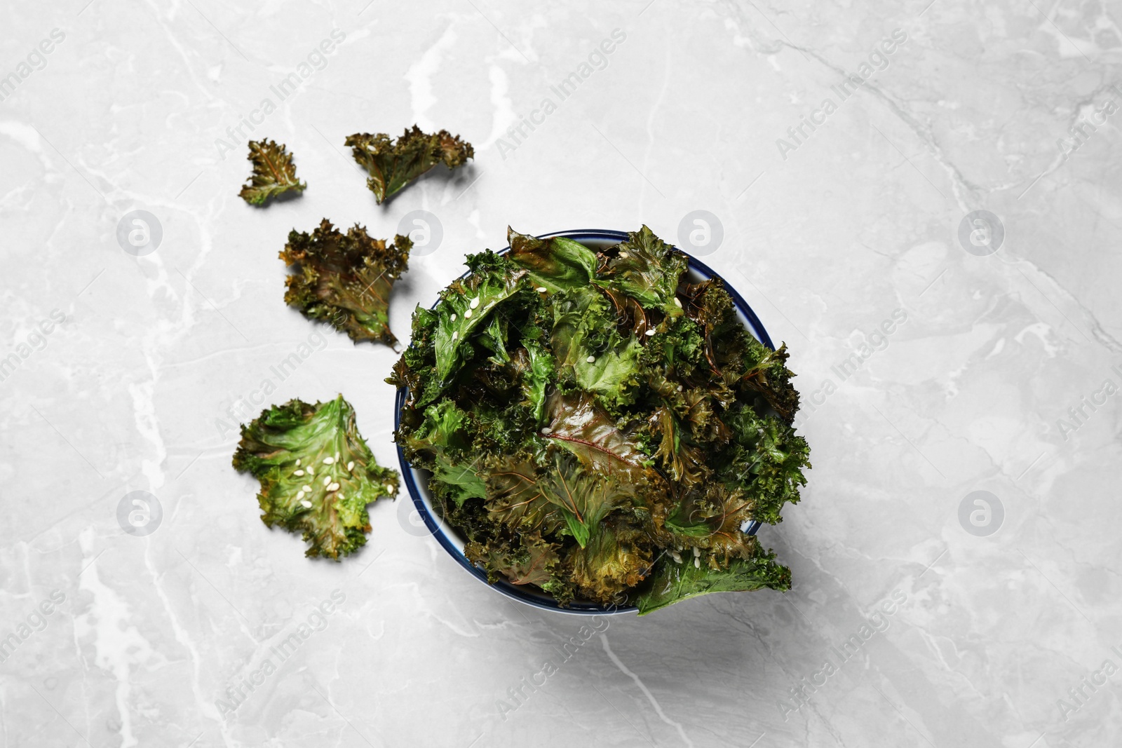 Photo of Tasty baked kale chips on grey marble table, flat lay