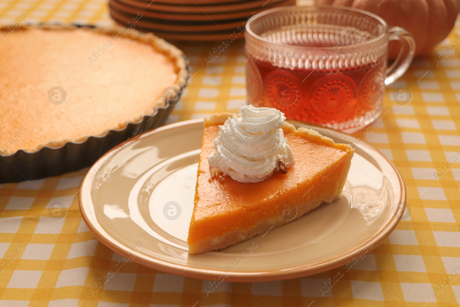 Photo of Piece of fresh homemade pumpkin pie served with whipped cream and tea on table