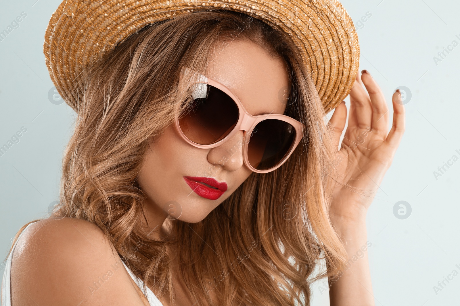 Photo of Young woman wearing stylish sunglasses and hat on light grey background