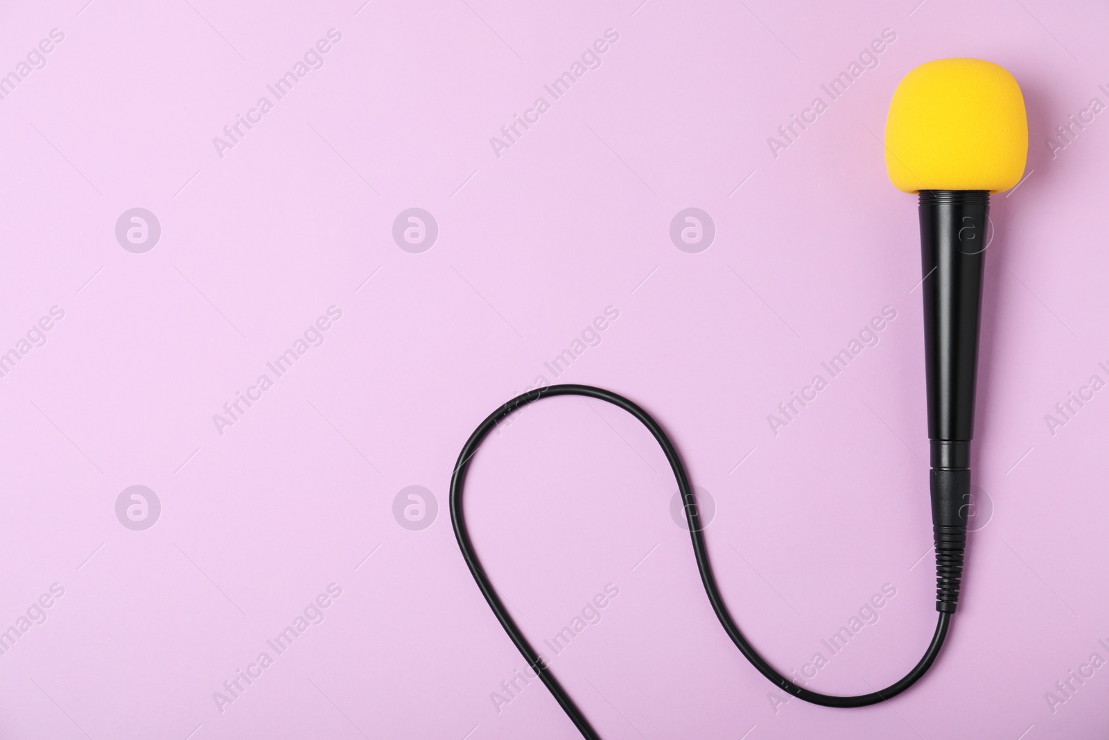 Photo of Modern microphone on color background, top view with space for text