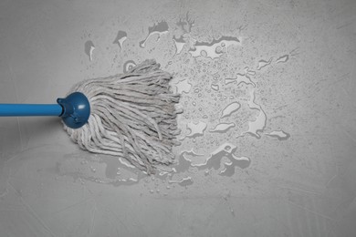 Photo of Cleaning grey floor with mop, top view. Space for text