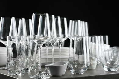 Photo of Set of empty glasses and dishware on table against black background